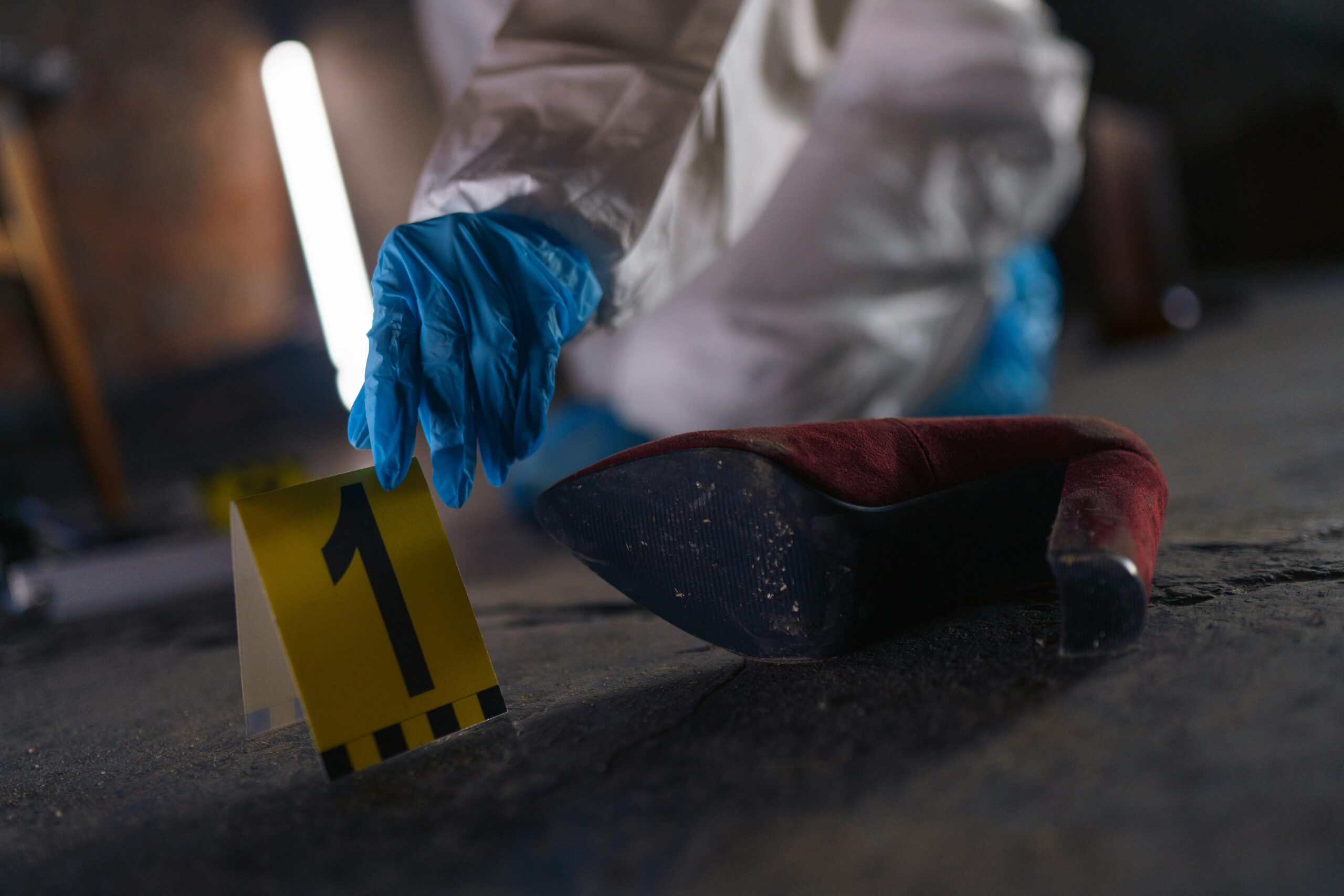 Crime scene investigation with shoe as evidence marked with number one and forensic glove.